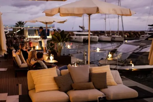 Cena al atardecer en Ibiza con vistas al mar, platos mediterráneos y terraza costera durante la hora dorada.