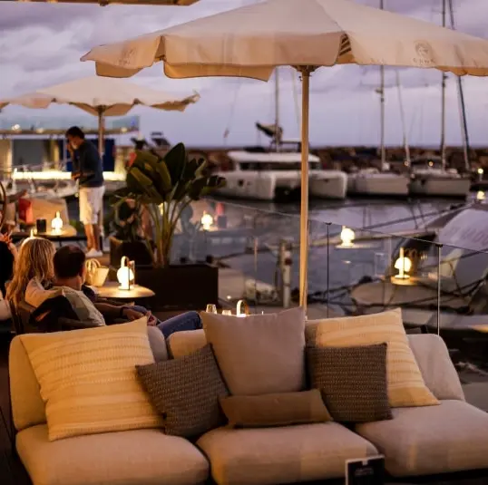 Cena al atardecer en Ibiza con vistas al mar, platos mediterráneos y terraza costera durante la hora dorada.