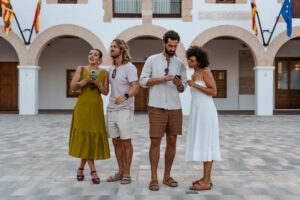 Viajeros explorando durante un tour gastronómico autoguiado, usando sus teléfonos para navegar entre restaurantes locales y lugares de comida escondidos en las Islas Baleares.