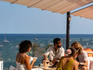 Amigos disfrutando de comida local y vino durante una experiencia gastronómica autoguiada en Ibiza