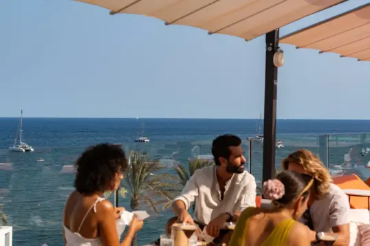 Amigos disfrutando de comida local y vino durante una experiencia gastronómica autoguiada en Ibiza