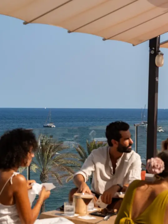 Amigos disfrutando de comida local y vino durante una experiencia gastronómica autoguiada en Ibiza