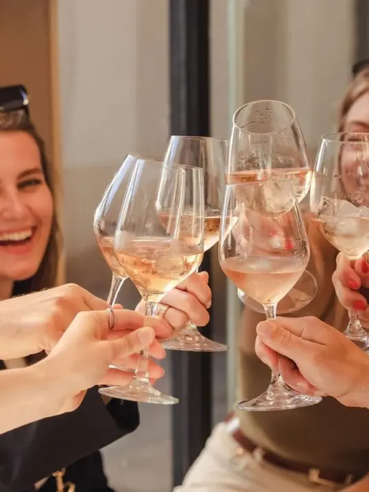 Amigas brindando con copas de vino rosado en un restaurante.