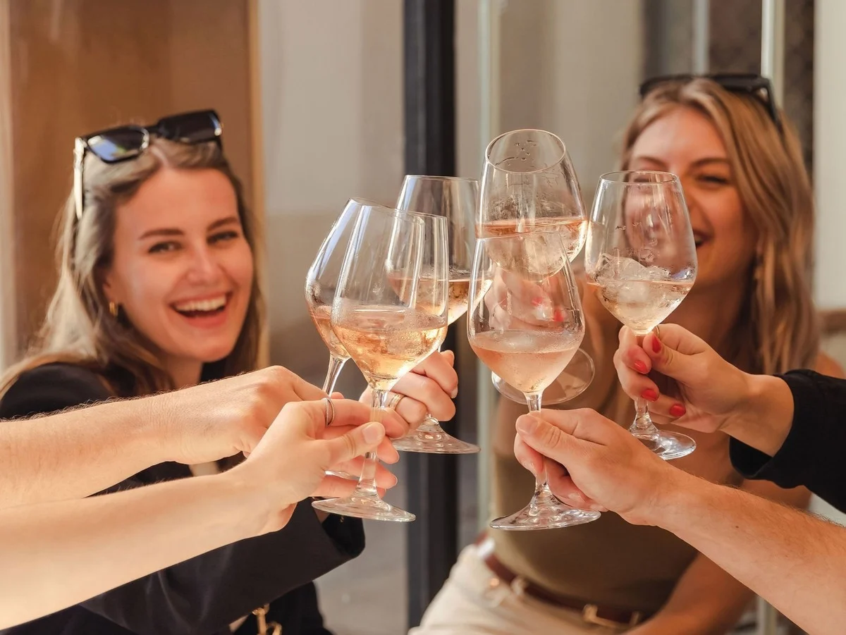Amigas brindando con copas de vino rosado en un restaurante.