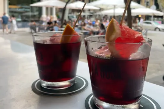 Two glasses of red vermouth served with ice and citrus garnish