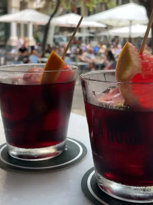 Two glasses of red vermouth served with ice and citrus garnish