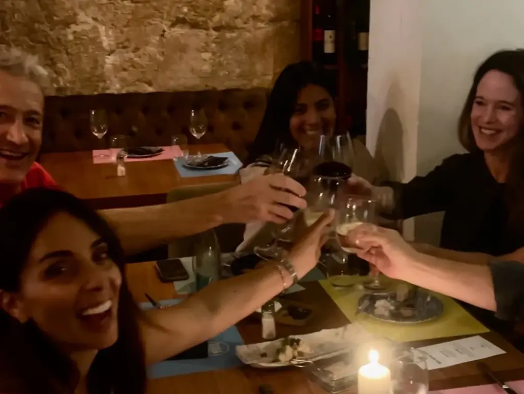 Social dinner club setting in Palma with people sitting together at a table, enjoying food, drinks and conversation.