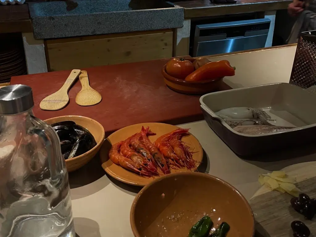 Hands-on cooking class at Moltak in Palma with fresh local ingredients, including seafood, vegetables and traditional Mallorcan dishes being prepared in a rustic kitchen setting.