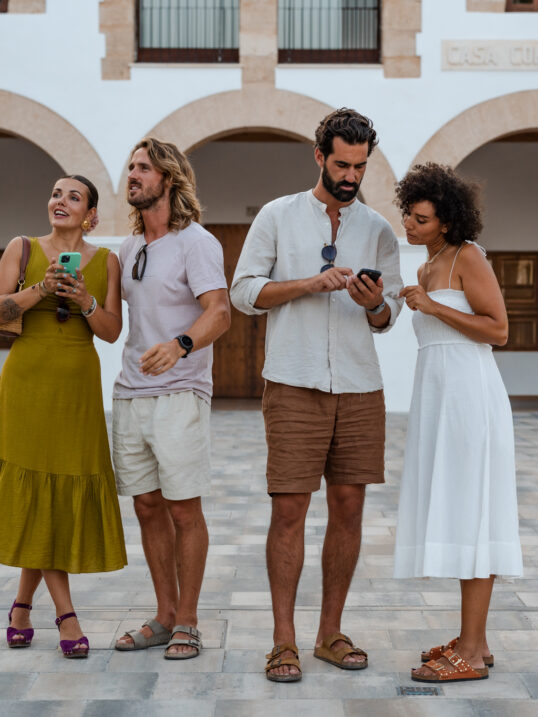 Travellers exploring during a self-guided food tour, using their phones to navigate between local restaurants and hidden food spots in the Balearic Islands.